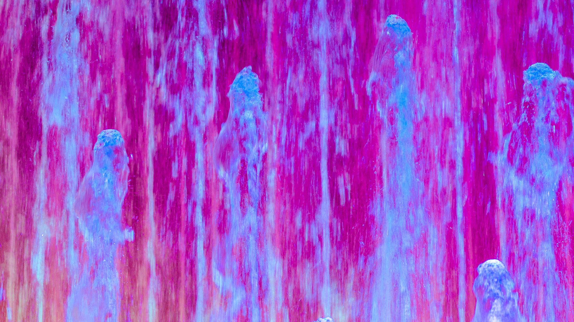 Colorful water fountains with violet and blue light effects.