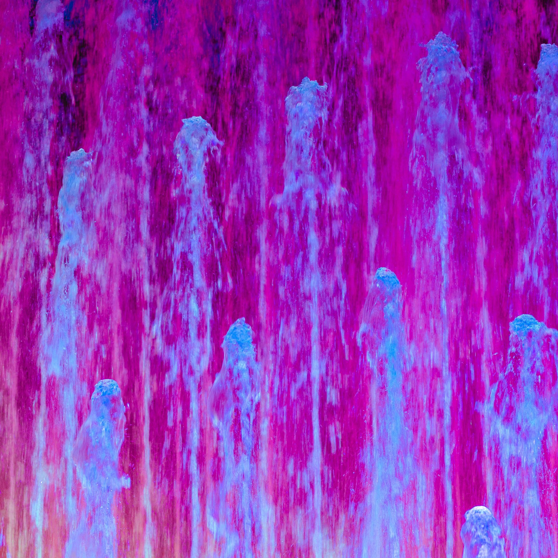Colorful water fountains with violet and blue light effects.
