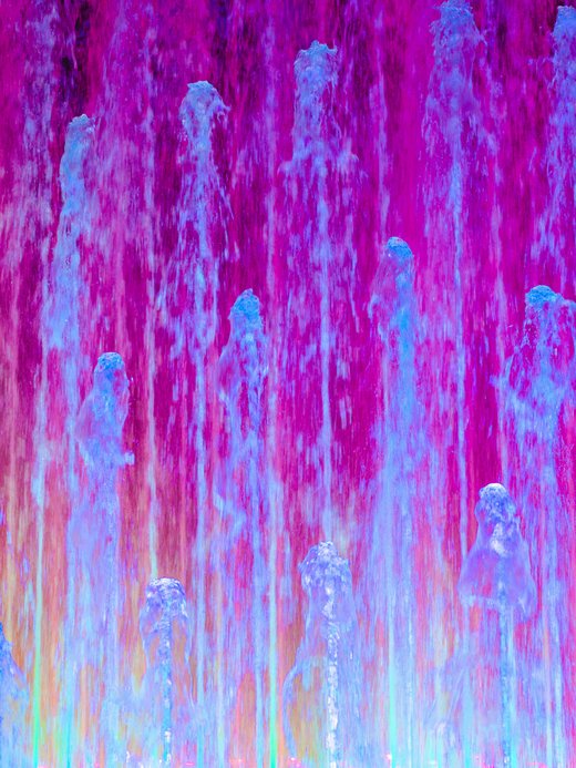 Bunte Wasserfontänen mit violetten und blauen Lichteffekten.