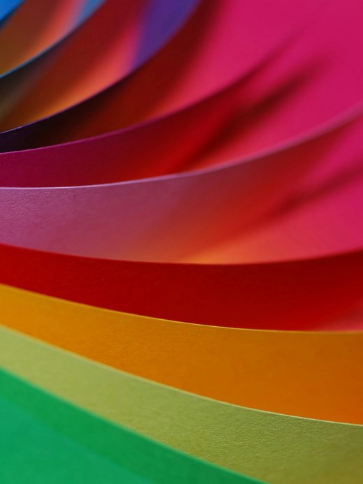 Bunte Papierbögen in Kurvenform angeordnet, intensive Farben.